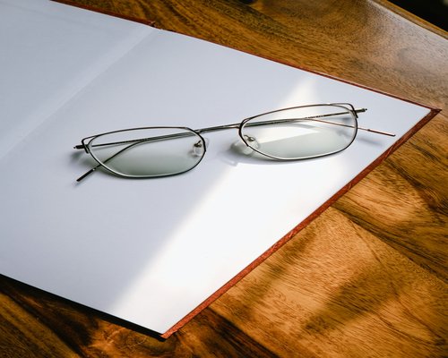 Libro aperto con occhiali su un tavolo di legno